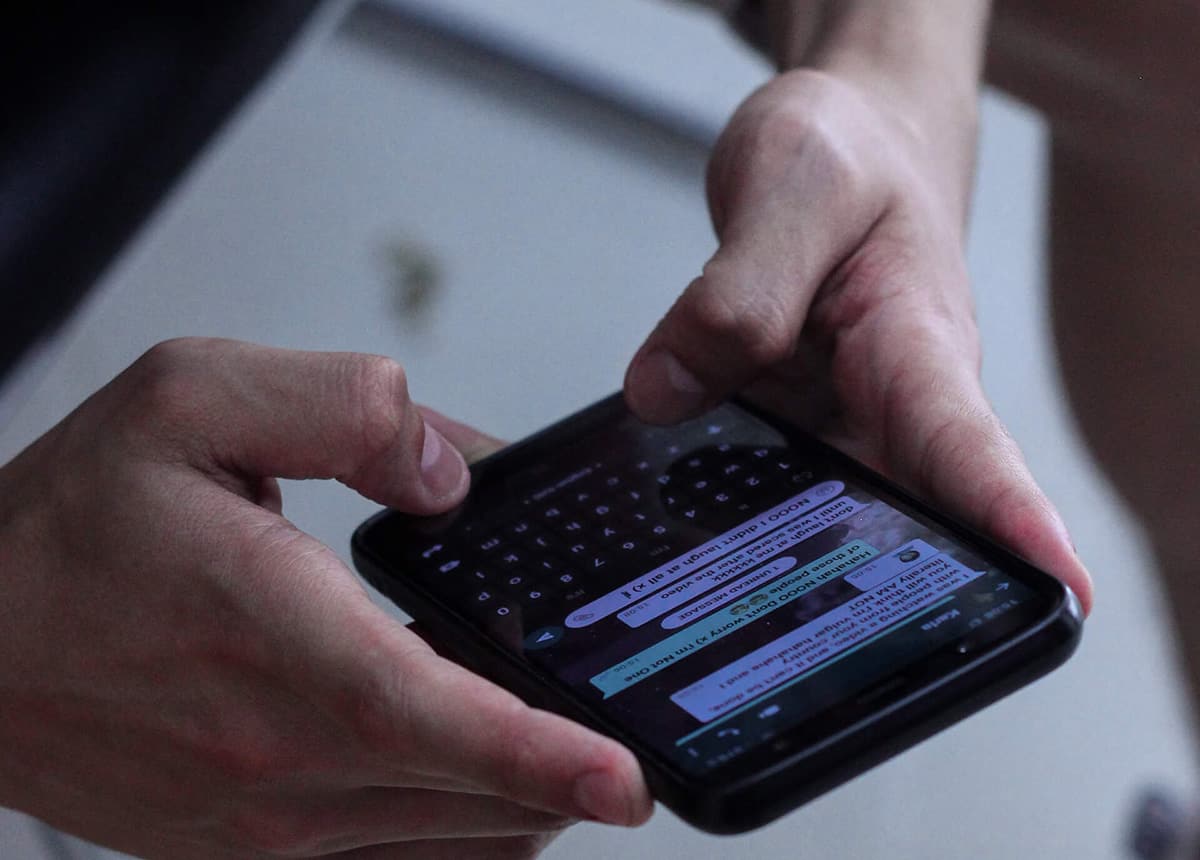 Person holding a smartphone displaying a chat application screen.