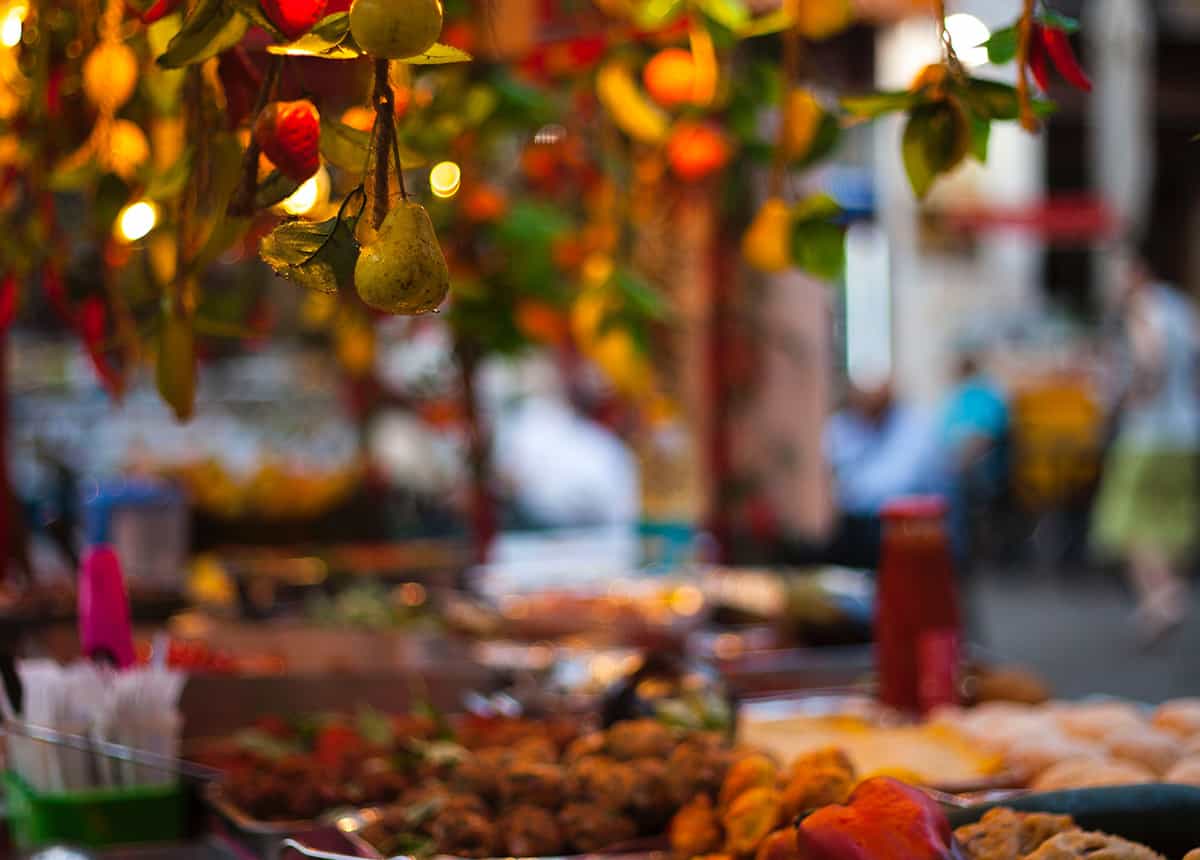 Close-up photo of fruits hanging and market stalls in the background.