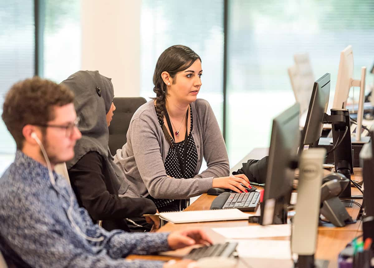 Office workers focused on computer screens in a modern workspace.