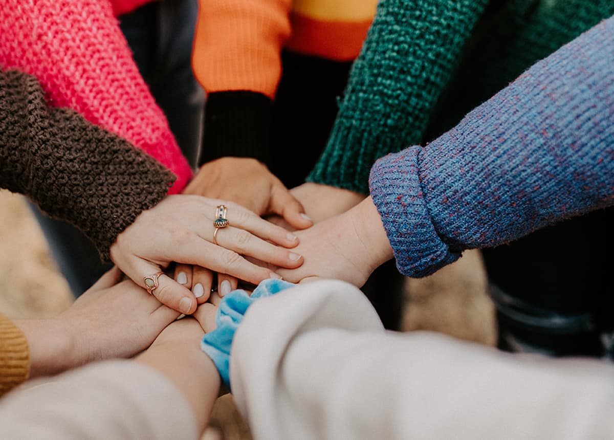 Close-up of a group of people's hands stacked together in a circle, symbolizing unity and teamwork.